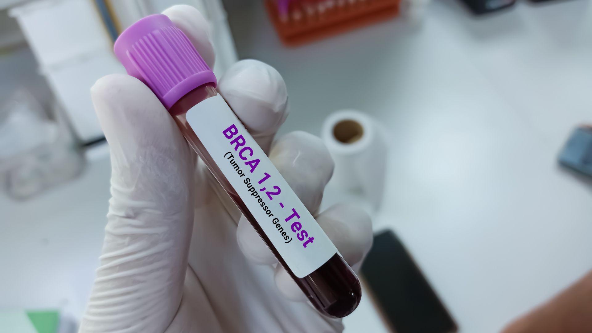 gloved hand holding blood test for BRCA gene