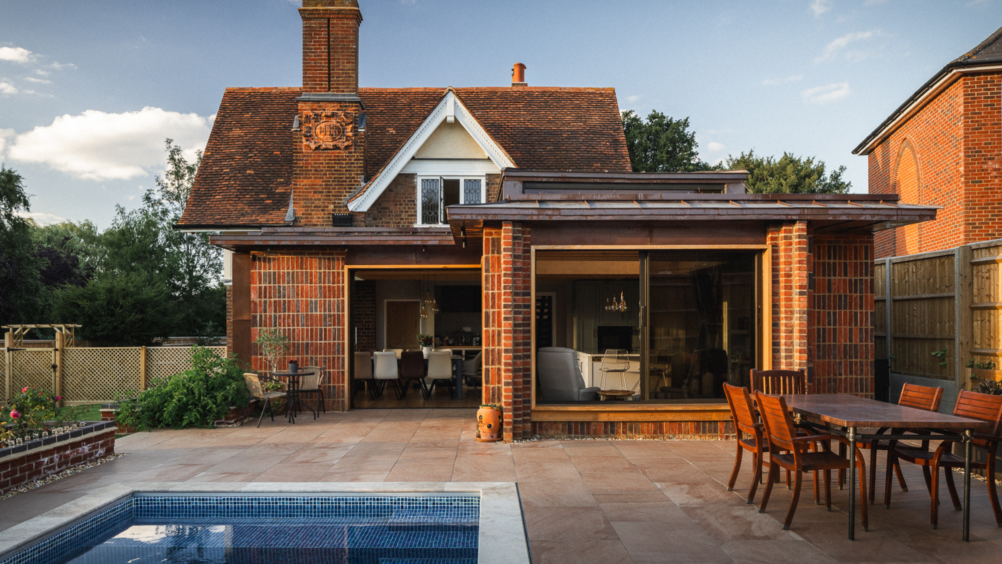 Exterior of back of the house with an L shaped extension, patio area and pool