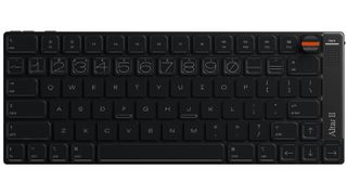 A top-down view of the black Altar II keyboard, showing its compact layout, outlined number keys and orange-striped M-Dial next to a speaker grille labelled &ldquo;caps&rdquo;.