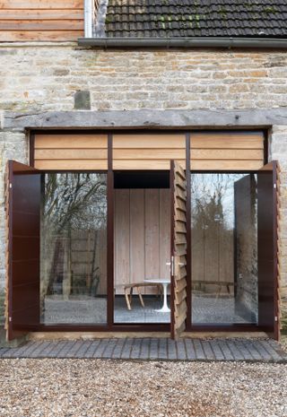 Exterior of Richard Parr home studio with large windows, wooden paneled doors and seating area with table