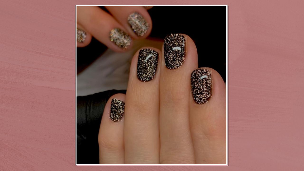 An image showing a close up of a black glittery manicure, in a white frame set against a dark pink watercolour-style background