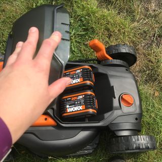 hand shutting battery compartment on Worx WG779 cordless lawn mower
