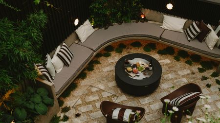 curved seating area with fire pit table and upholstered bench with brown striped textiles