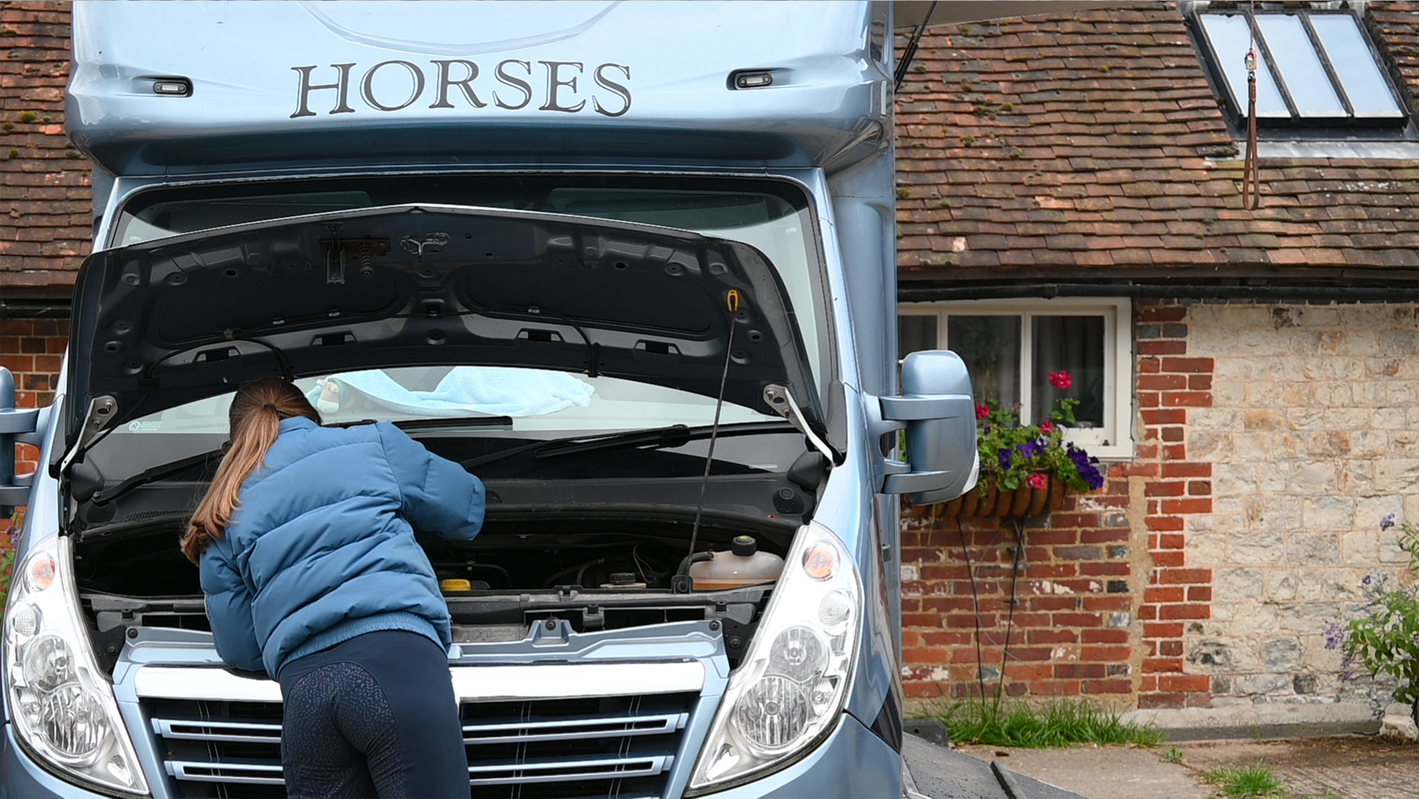 Female checking under the bonnet of horsebox