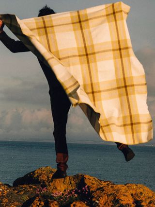 Person with check blanket on rock