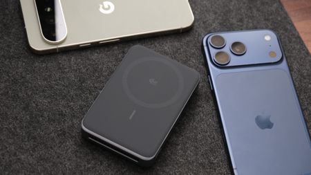 Anker MagGo Power Bank 2 Pro lying beside two smartphones, showing its Qi2 wireless charging surface.