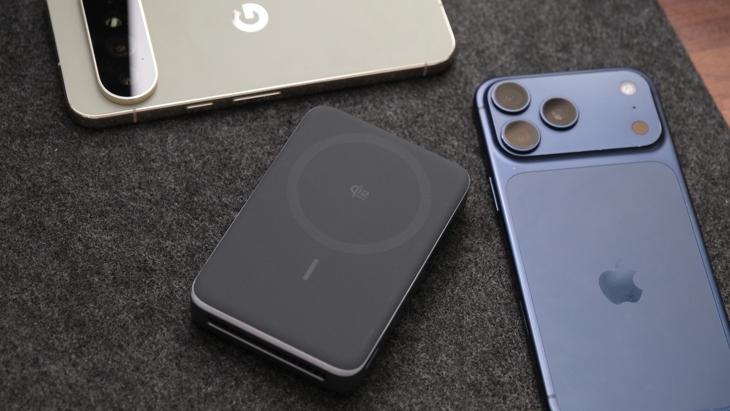 Anker MagGo Power Bank 2 Pro lying beside two smartphones, showing its Qi2 wireless charging surface.