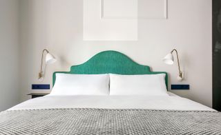 The Fritz bedroom with light grey walls, kingsize bed with green padded headboard and wall mounted lamps