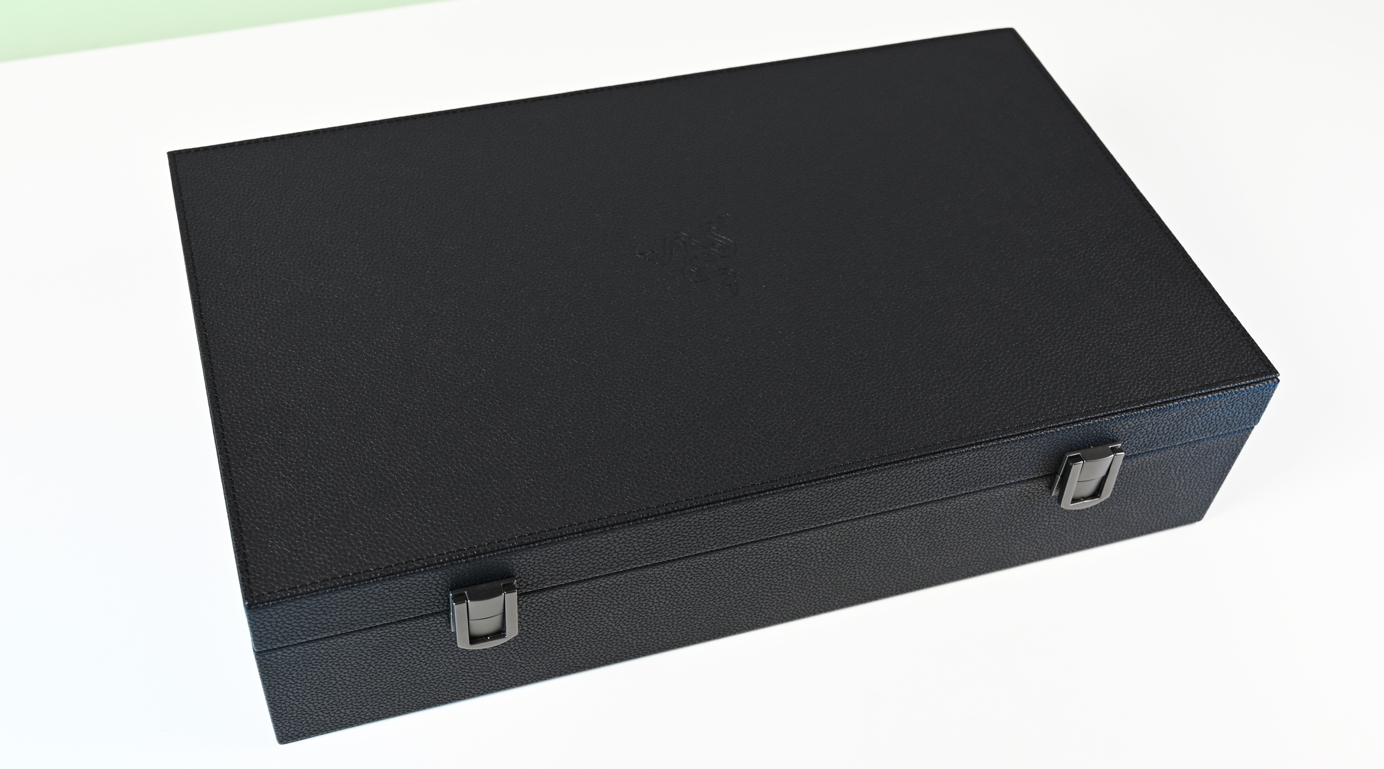 A large, closed black storage case with a textured leather-style finish, front metal clasps, and a subtly debossed Razer logo on the lid.