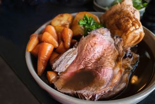 Close up of Christmas dinner including roast beef, yorkshire puddings and veg with gravy