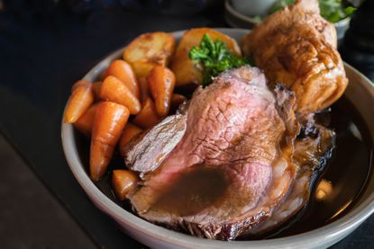 Close up of Christmas dinner including roast beef, yorkshire puddings and veg with gravy