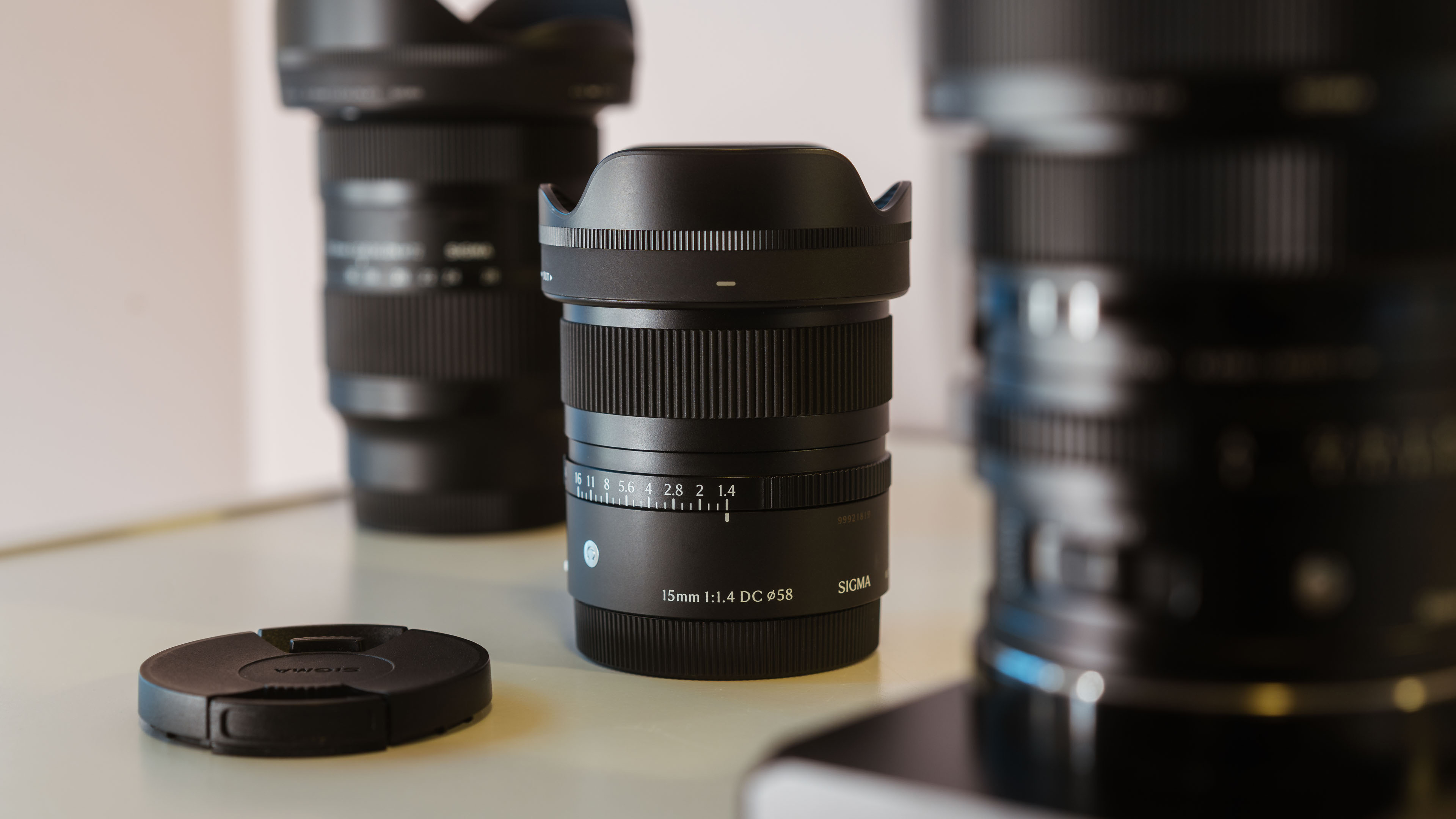 The Sigma 15mm f/1.4 DC Contemporary sitting on a table with other Sigma lenses