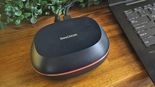 A SanDisk Desk Drive Desktop 8TB SSD sitting on a wooden desk next to a laptop