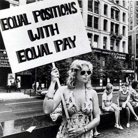 Lone woman stands on corner protesting unequal pay for women