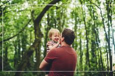 Father holding his son, and looking at each others faces in a wooded area