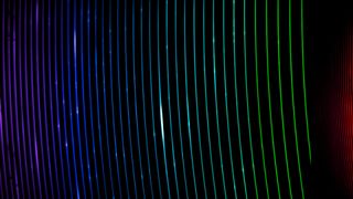 A series of brightly coloring curved colored lines creating strips of rainbow over a dark black background