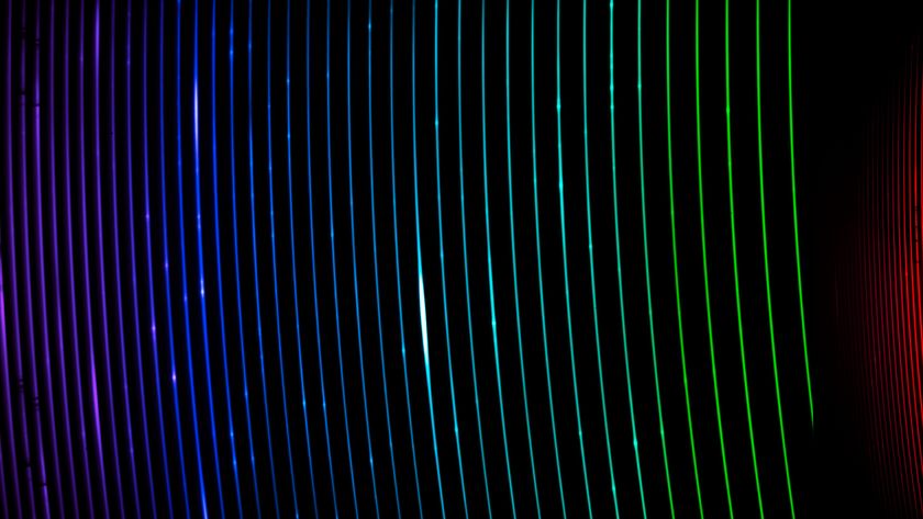 A series of brightly coloring curved colored lines creating strips of rainbow over a dark black background
