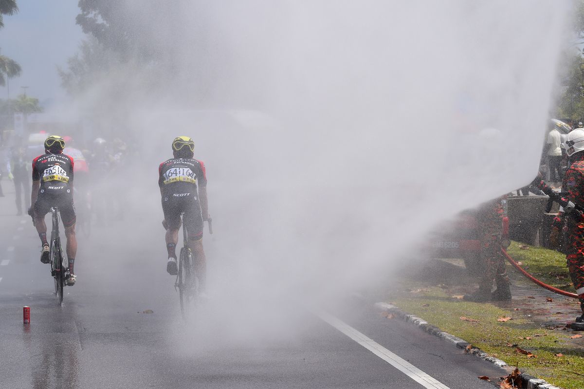 Riders are sprayed with water after crossing the line to help cool down