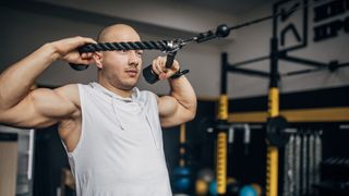 Man performs face pull shoulder exercise using cable machine