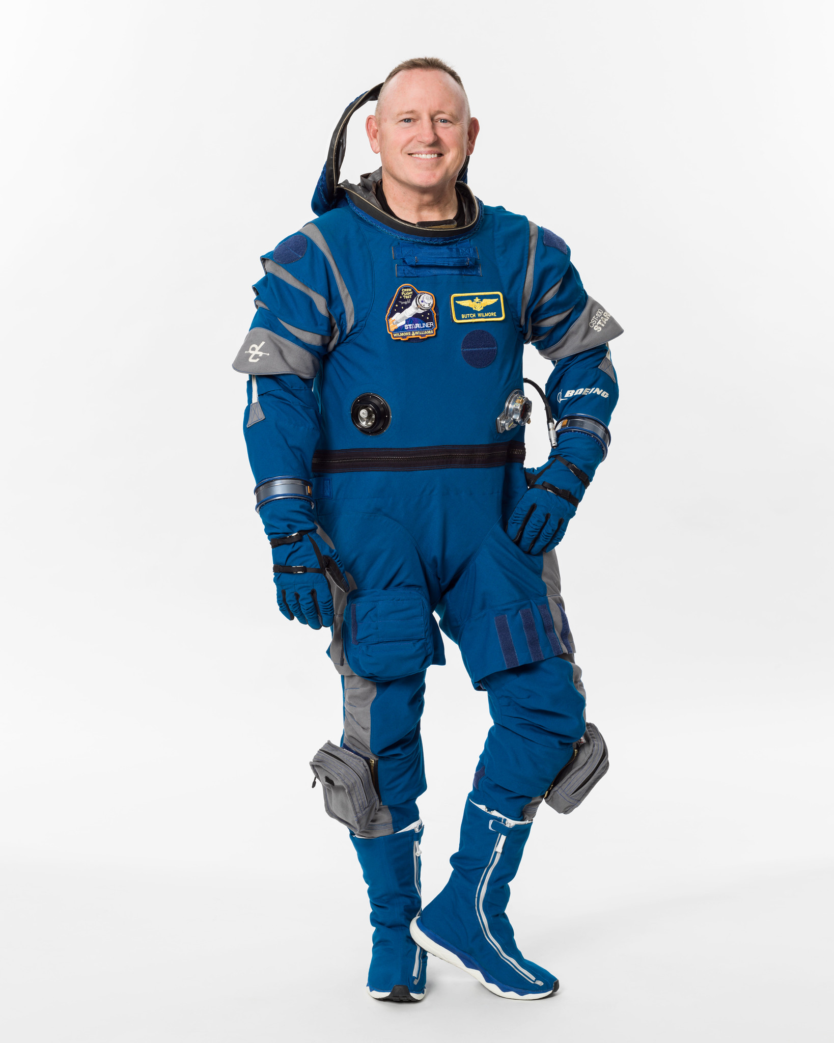 an astronaut poses for a portrait in a blue flight suit