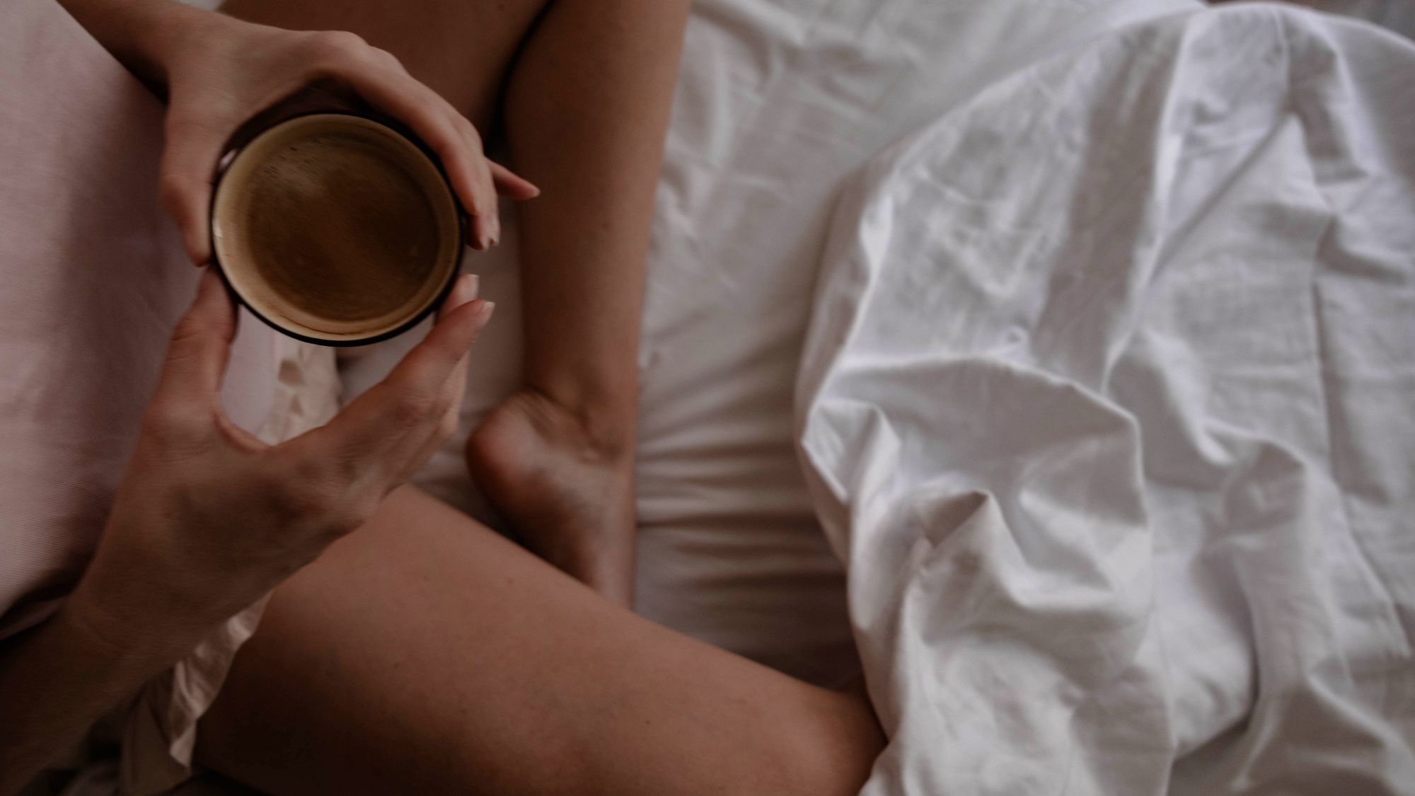 A woman drinking a cup of tea in bed