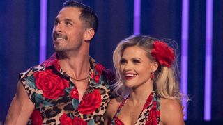 Danny Amendola and Witney Carson await their notes from the judges during the Dancing With The Stars Semi-Finals. Both are wearing rose and leopard print outfits.