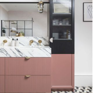 bathroom with pink vanity cabinets and white marble sink