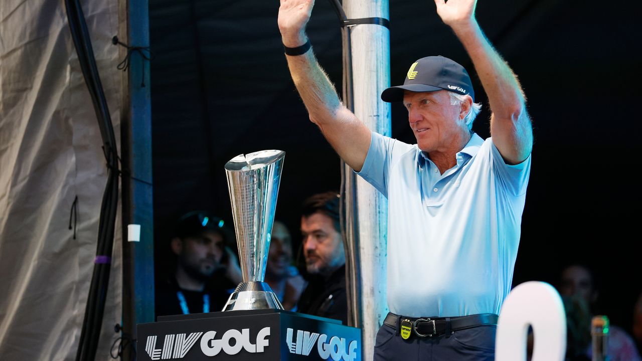 Greg Norman acknowledges the fans at the 2023 LIV Golf Team Championship, with the trophy by his side