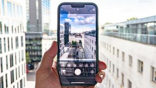 An iPhone being held up to take a photo of a London skyline