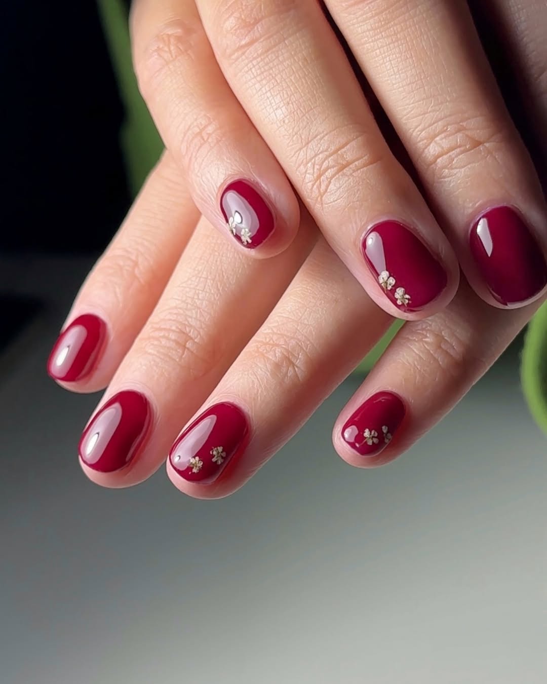 a person wearing red nails with a small flower design on the ring and pinky fingers