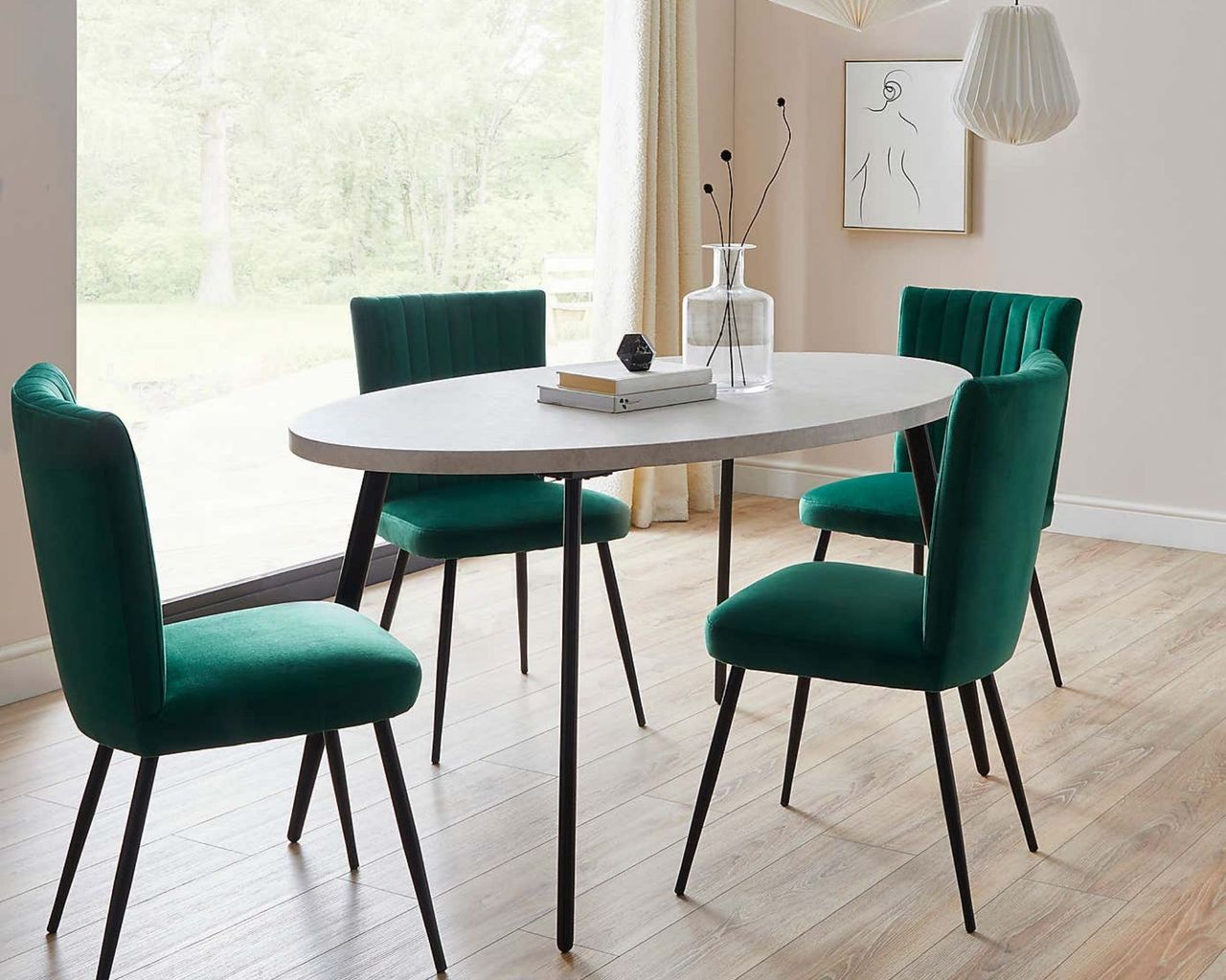 Zuri Concrete Effect Oval Dining Table in room with green velvet chairs