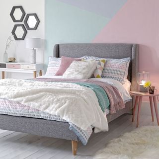 bedroom with multi colour wall grey bed with designed cushion and white wooden flooring