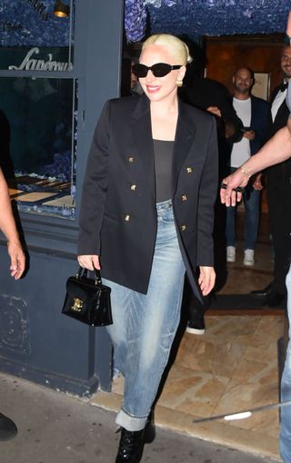 Lady Gaga wears a black blazer with jeans and a bag, all by Celine