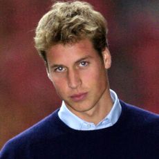 Prince William has big blond hair and piercing eyes, he wears a light blue shirt with a dark blue sweater over the top, on his first day at St Andrews University in Scotland