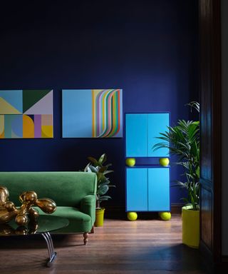 dark blue living space with green sofa, bright blue cabinets and colorful graphic artwork on walls