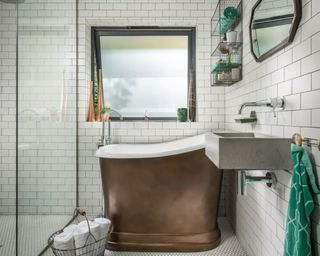 A small tiled bathroom with shower and copper-finish bathtub