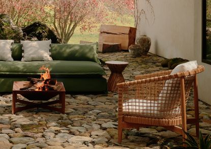 A backyard with a green outdoor sofa and firepit