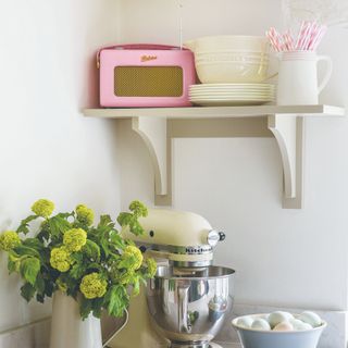 A kitchen with a stand mixer and a vase of hydrangeas and a Roberts radio on a shelf