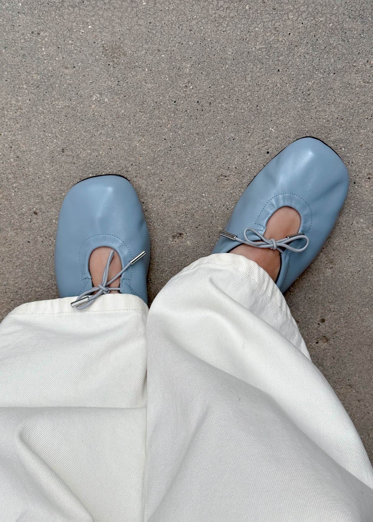 Shot of white trousers, blue leather ballet flats