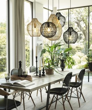 mix of black and cream rattan lights hung over dining table in room with large floor to ceiling windows