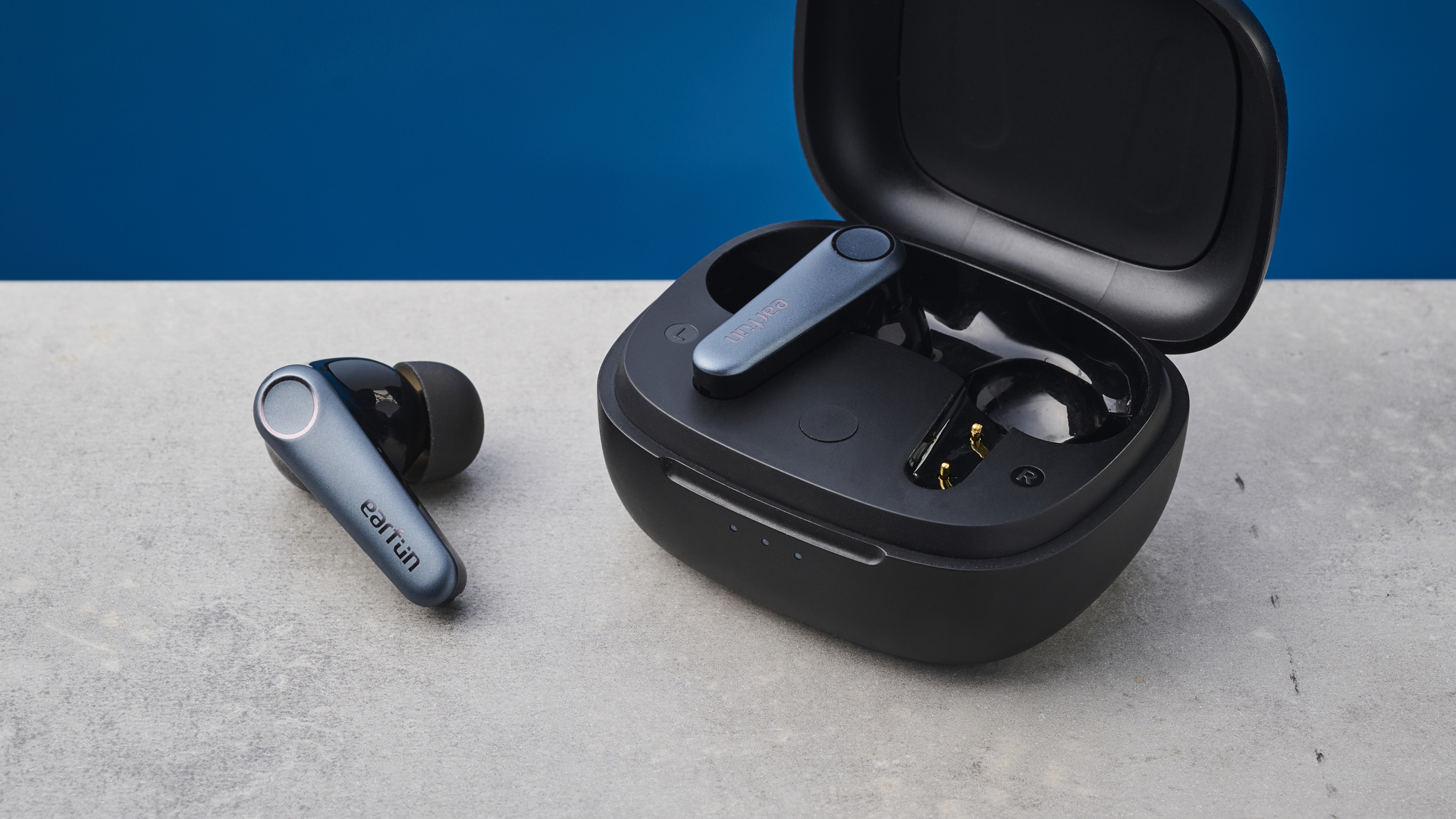 A pair of EarFun Air Pro 3 wireless earbuds – one earbud sitting in the case and the other sitting outside