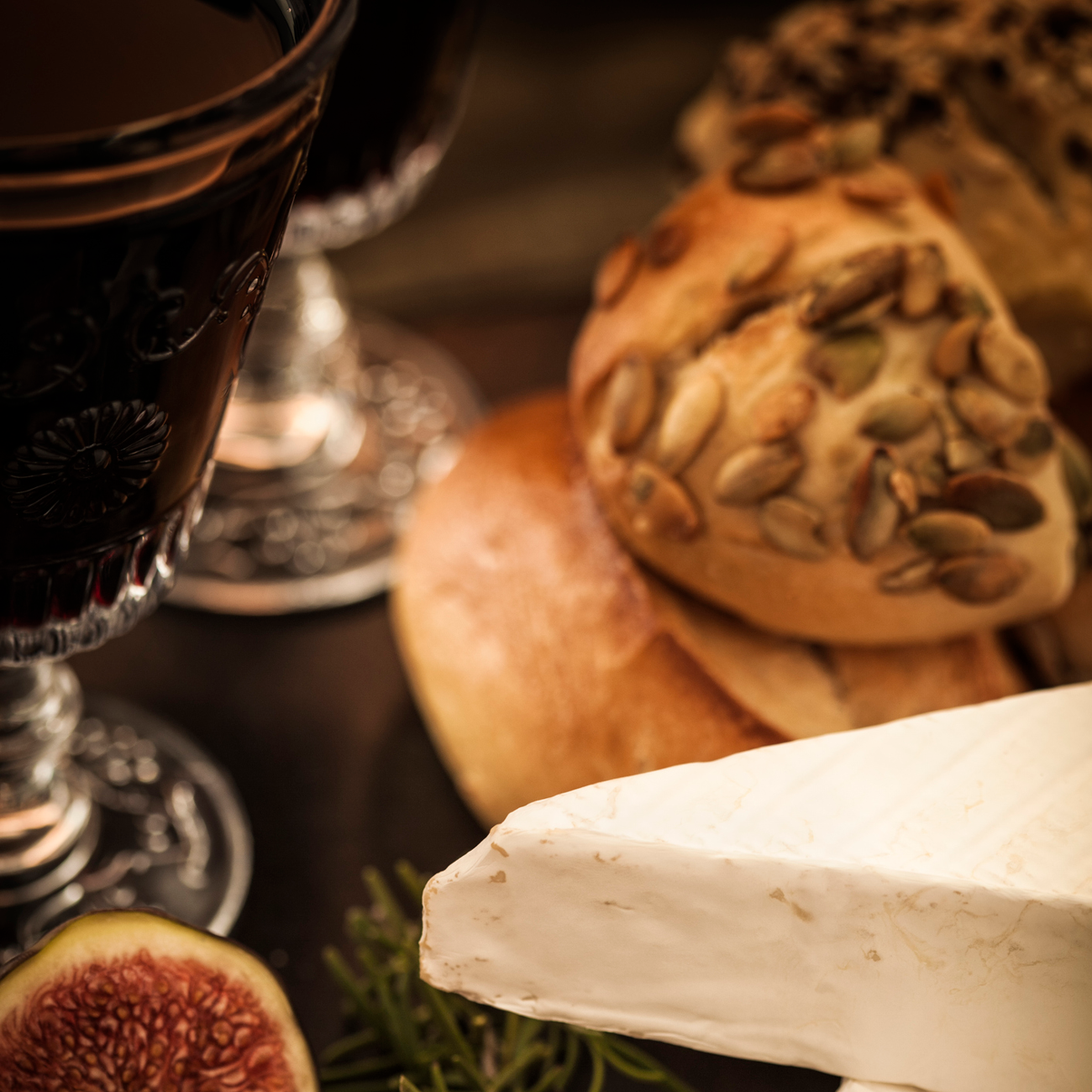 A glass of Port next to a slice of brie, a fig and a bun