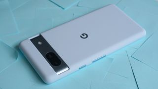 En lyseblå Google Pixel 7a ligger med bagsiden opad på en seng af blå post-it-sedler