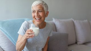 woman drinking a glass of milk on her sofa