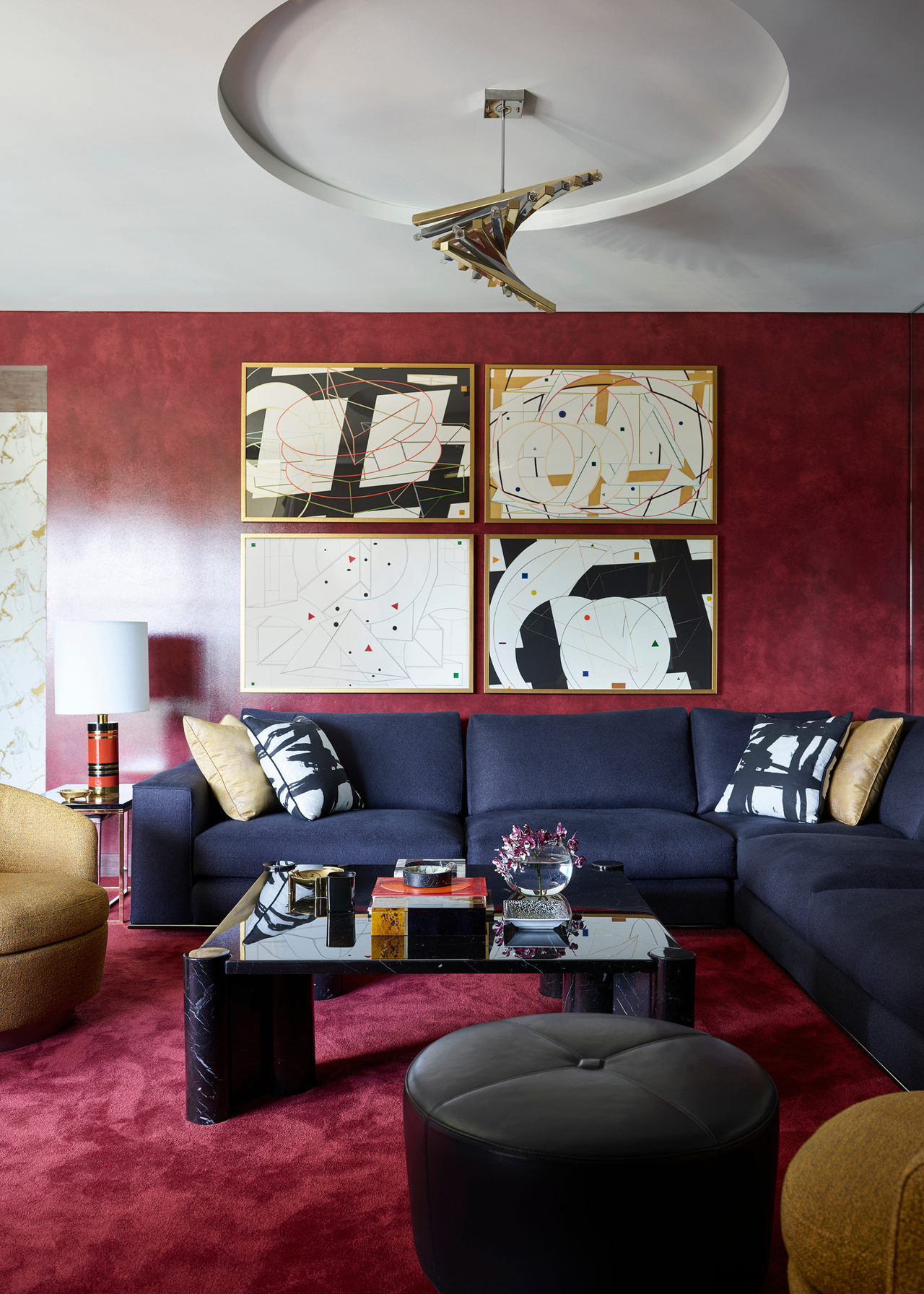 Greg Natale's apartment living room with red walls and carpet and blue corner sofa with a statement coffee table and artwork