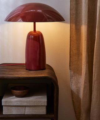 H&M Home US Furniture and Lamp launch campaign image with red lacquered lamp, wooden bowl and upholstered storage box