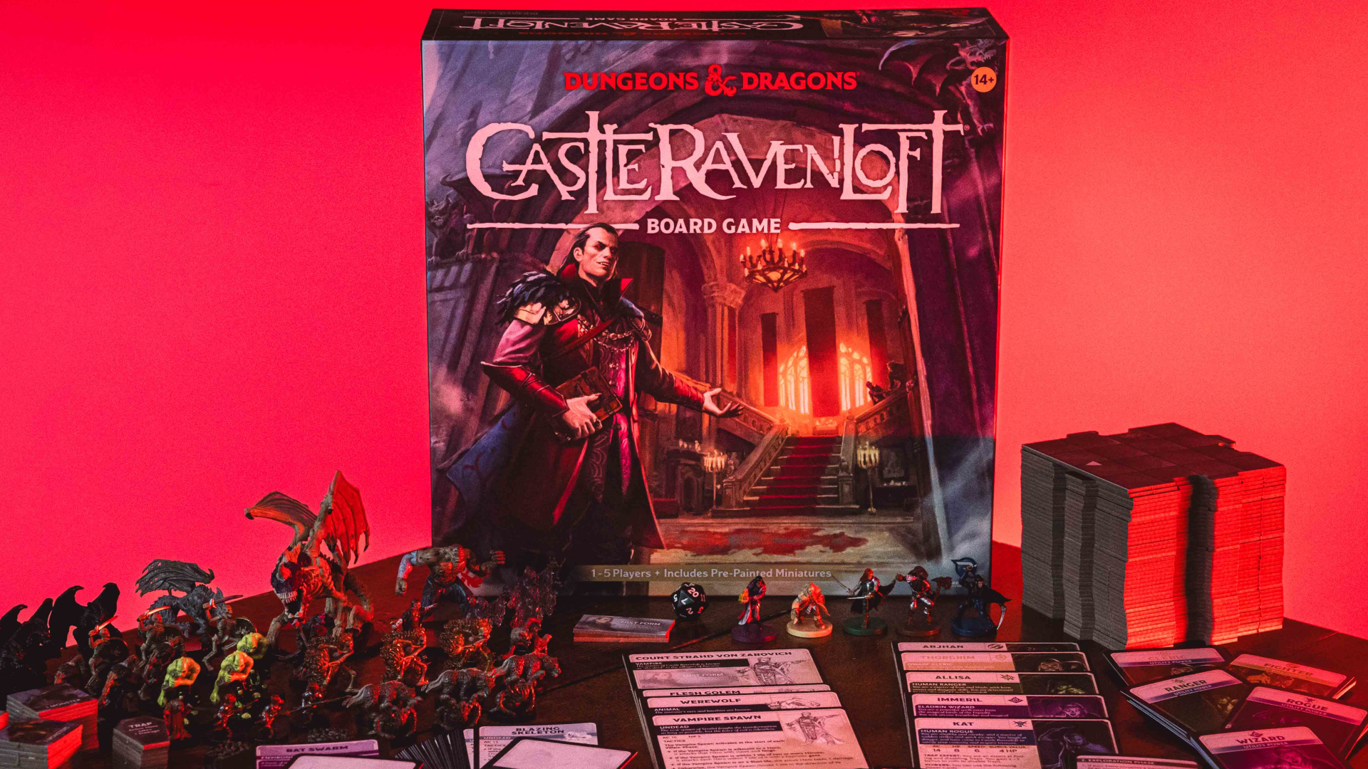 Castle Ravenloft board game box and contents arranged on a dark table, against a pink background