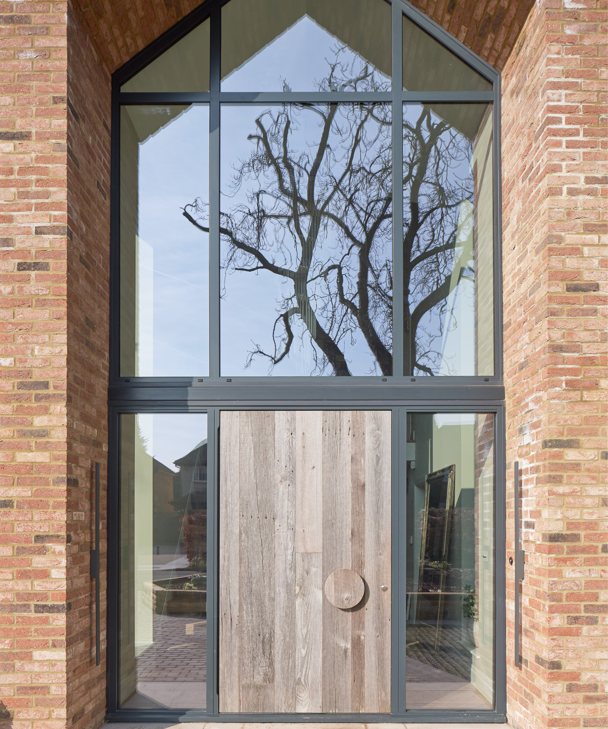 large wooden door with round wooden handle, large glazed panels to side and above