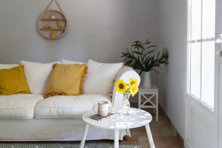 Living room with white sofa, sunflowers and cup on table at home