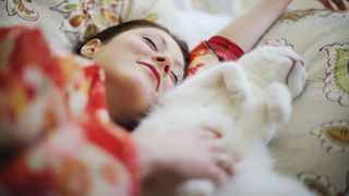 Cat sleeping on a pillow next to a woman's head